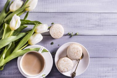 Sabah kahvesi, pasta makaronu ve beyaz ahşap arka planda bahar lale çiçekleri. Düz kat. Kadınlar için güzel bir kahvaltı.