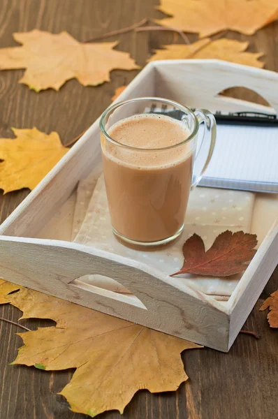 Kopje koffie met melk op houten achtergrond met najaar verlaat — Stockfoto