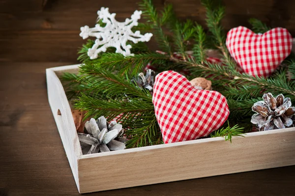 Vánoční koncepce (dekorace). Dvě červené ruční srdce s kuželem na rustikální dřevěné pozadí — Stock fotografie