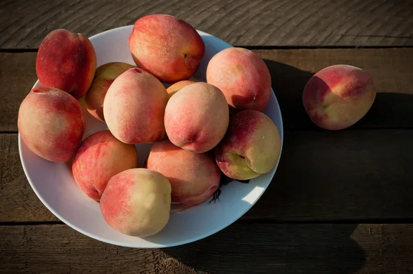 Bowl with some peaches on old wooden table — Stock Photo, Image