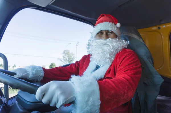 Noel Baba araba kullanıyor. Noel Baba takan ve mutlu gülümseyen kamyon şoförü. Ulaştırma ve dağıtım işindeki işçiler bayram kutlamalarında çalışıyorlar. Mutlu Noeller.
