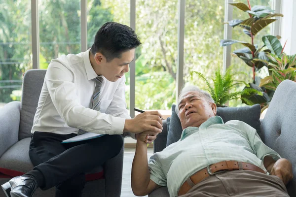 Asian Fat old man meets a doctor at clinic. A white-haired senior man consulting doctor about health at nursing home. Retired male medical consultation By specialist psychiatrist At mental hospital