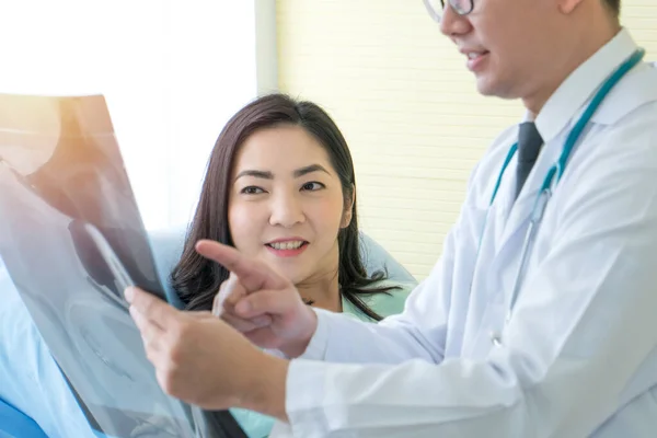 Patient and doctor discuss X-ray results in clinical laboratories. Young Asian woman, having cancer, medical consultation with specialist at treatment center. Healthcare, Disease therapy, and medical
