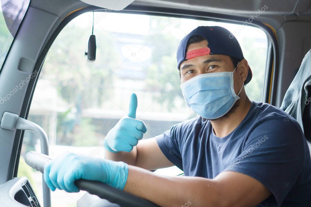 Professional truck driver Asian man wear mask And medical gloves to prevent coronavirus while driving. owner business transportation Male Mature adult happy smiling pride success  Long time service.