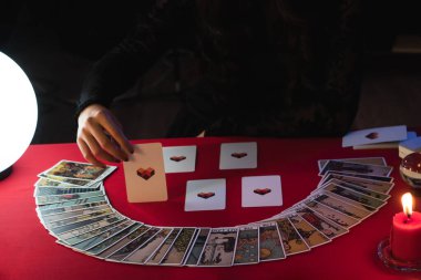 Falcı çingene stili, elinde mum ışığında elinde tarot kartları okuyarak geleceği kontrol ediyor. Falcılık, astroloji, ritüel, kehanet, sihir, cadı, büyücü, Cadılar Bayramı.