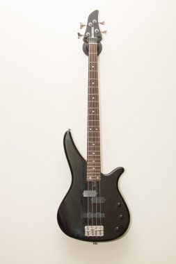 black bass electric guitar hanging on the wall