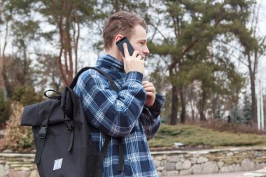 adam telefonda konuşurken bir sırt çantası ile