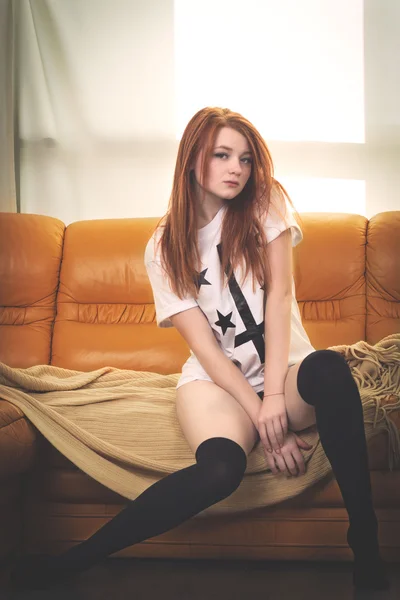 Dai capelli rossi ragazza in calze sul divano — Foto Stock