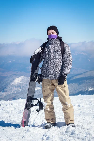 De man in de besneeuwde bergen met een snowboard — Stockfoto