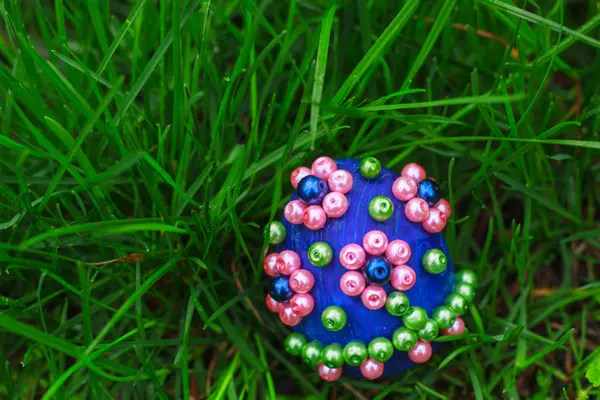 Modrý velikonoční vajíčko s květin v trávě — Stock fotografie