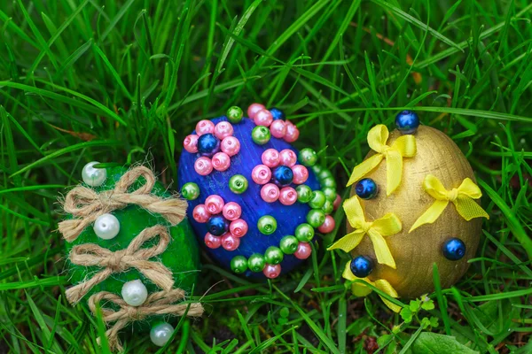 Три красивые пасхальные яйца на зеленой траве — стоковое фото