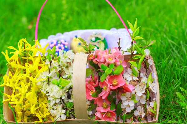 Cesta de flores y una cesta con huevos de Pascua — Foto de Stock