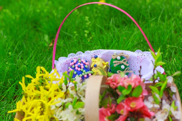 Cesta de flores y una cesta con huevos de Pascua — Foto de Stock