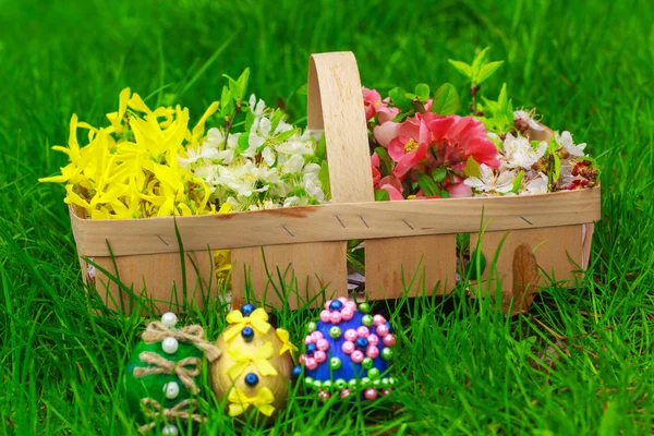 Пасхальные яйца и корзина с цветами на траве — стоковое фото