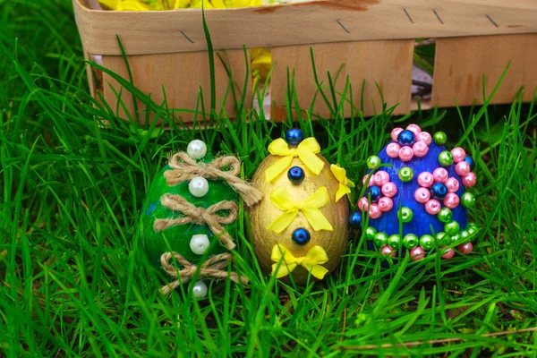 Huevos de Pascua y una cesta con flores en la hierba — Foto de Stock