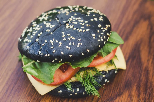 Hamburguesa negra en una tabla de madera — Foto de Stock