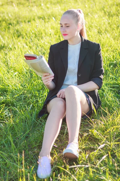 Mujer sentada en la hierba leyendo un libro —  Fotos de Stock