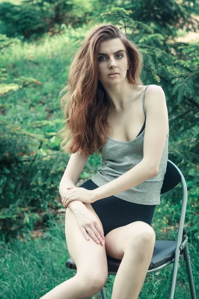 Junges weibliches Modell sitzt auf einem Stuhl in der Natur — Stockfoto