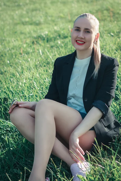 Çimenlerin üzerinde oturan güzel kadın gülümseyen kız — Stok fotoğraf