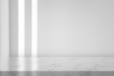 Boş duvar arkaplanı ve güneş ışığı olan beyaz mermer masa, ürün gösterimi için ideal.