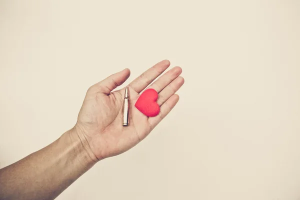 Hand holding a bullet and heart — Stock Photo, Image