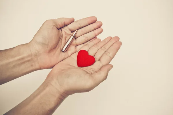 Hand holding a bullet and heart — Stock Photo, Image