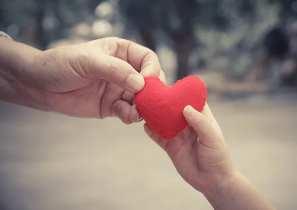 Manos sosteniendo un corazón rojo — Foto de Stock