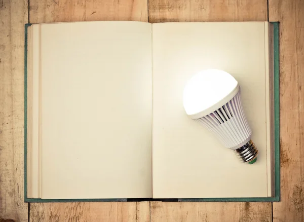 LED lightbulb on open book — Stock Photo, Image
