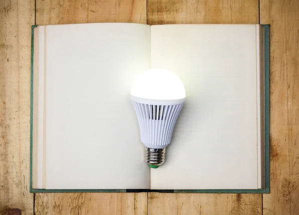 LED lightbulb on open book — Stock Photo, Image