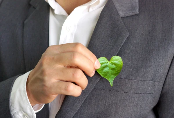 Empresário segurando uma folha de coração verde — Fotografia de Stock