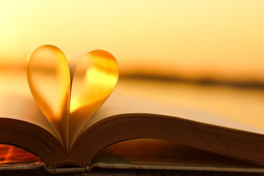 Kalp günbatımı arka plan üzerinde kitap sayfalarından