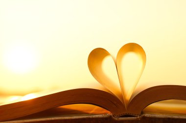 Kalp günbatımı arka plan üzerinde kitap sayfalarından
