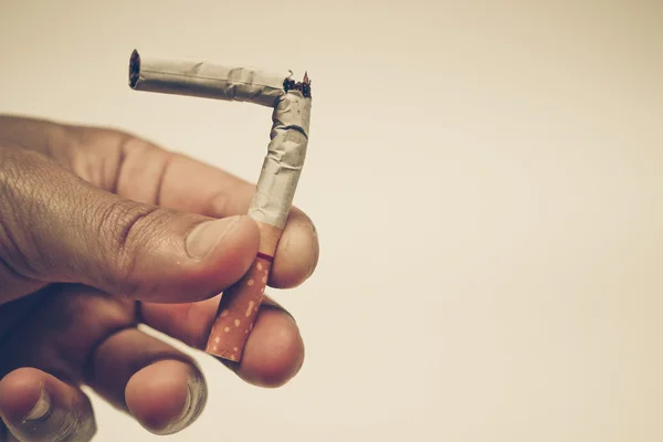 Hand destroying cigarette on bright background — Stock Photo, Image