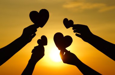 Hands holding hearts against sunset clipart