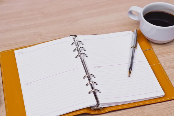 Cuaderno, taza de café y bolígrafo en la mesa — Foto de Stock