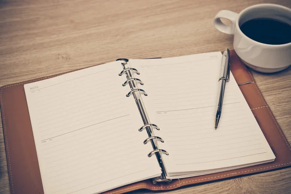 Caderno, xícara de café e caneta na mesa — Fotografia de Stock