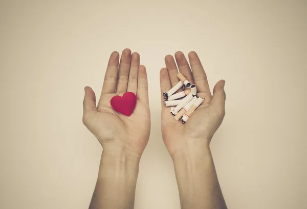 Hands hold heart and cigarettes — Stock Photo, Image