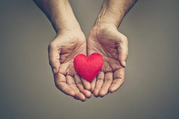 Mani femminili che tengono il cuore rosso — Foto Stock