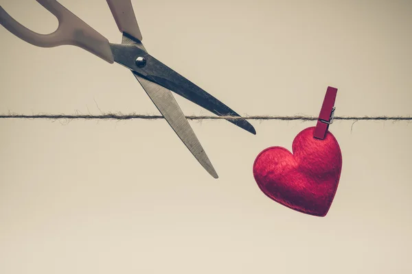 Tesoura tentando cortar um coração vermelho — Fotografia de Stock