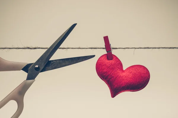 Tesoura tentando cortar um coração vermelho — Fotografia de Stock