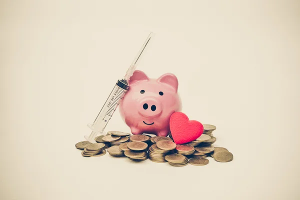 A pink piggy bank, a syringe with needle — Stock Photo, Image