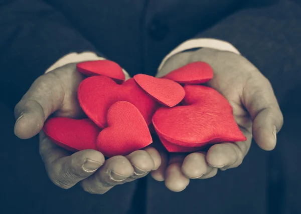 Empresário segurando corações vermelhos — Fotografia de Stock