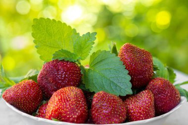 Yeşil arka planda beyaz tabakta limon aromalı çilek.