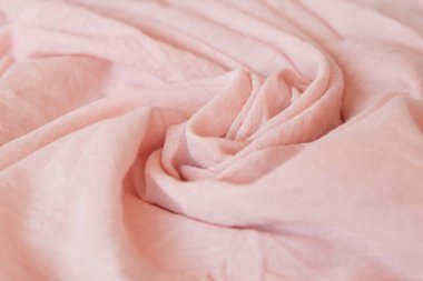 Tozlu gül, açık pembe bez bebek. Yumuşak muslin bebek battaniyesi arka planı. Pamuk giysi ve tekstil. Doğal organik kumaş dokusu. Kapat..