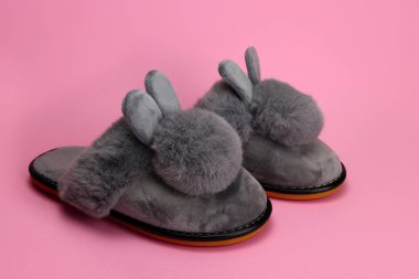 Yumuşak kulaklı terlikler, pembe arka planda rahat kadın ayakkabıları.