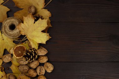 Ahşap bir masanın arka planında sarı yapraklar, fındıklar ve konilerin sonbahar kompozisyonu. Düz Yat. Metin için alanı kopyala
