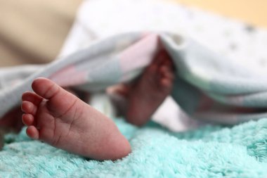 Bebek, yeni doğmuş bebeğin ayakları battaniyeye yakın.