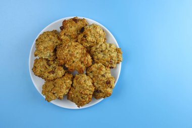 Mavi arka planda kuru üzümlü ev yapımı yulaflı kurabiyeler.