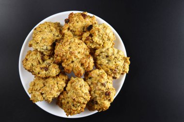 Siyah arka planda kuru üzümlü ev yapımı yulaf ezmeli beyaz tabak.