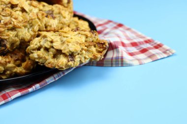 Siyah arka planda kuru üzümlü ev yapımı yulaflı kurabiyeler.